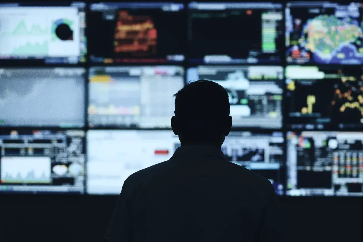 An operator in front of a wall of dashboard screens in a control room